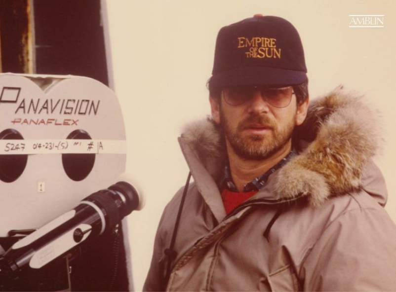 On location shooting Empire of the Sun, proudly wearing a crew hat for the film while he creates it.